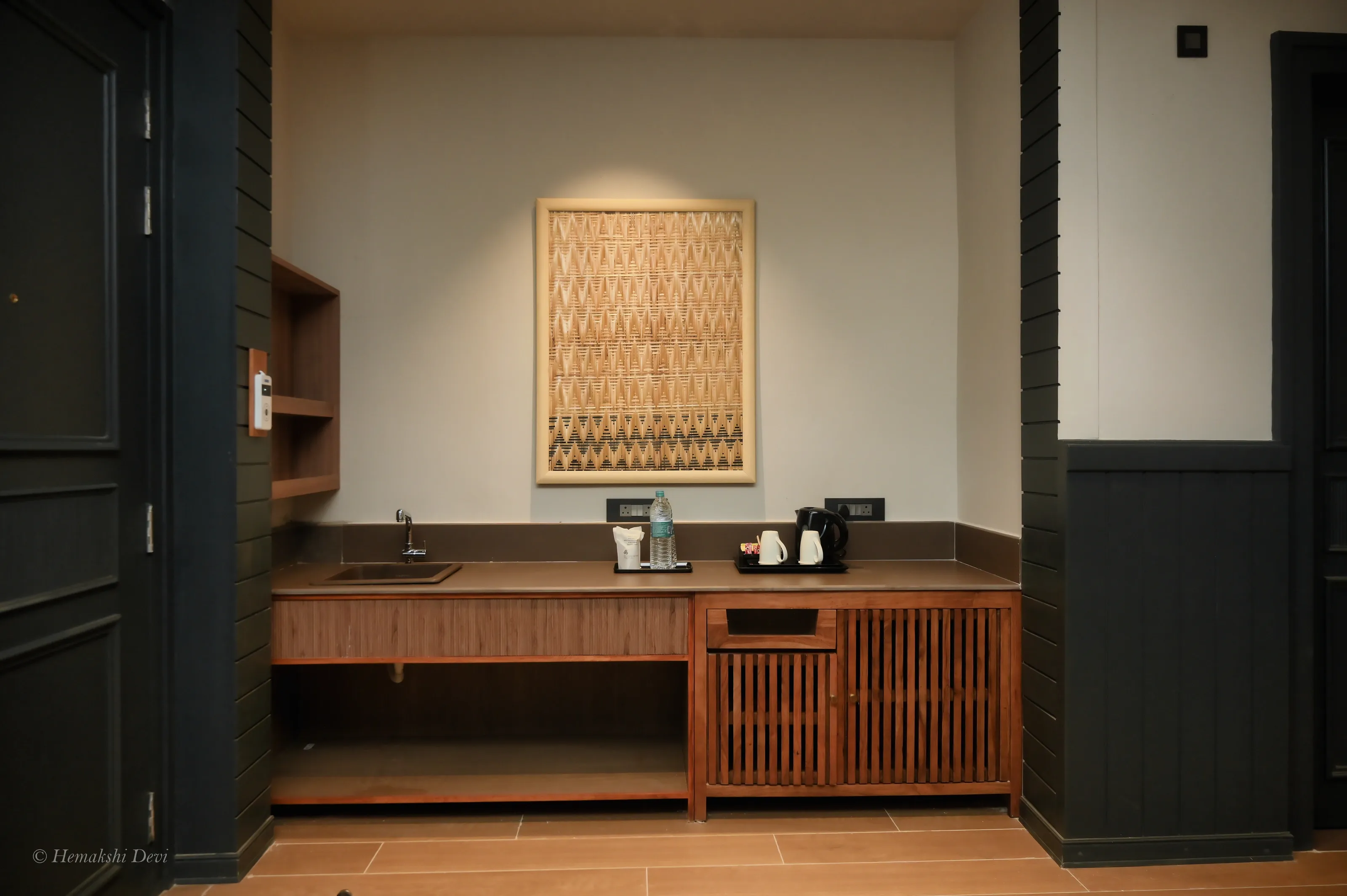 Bamboo-weave art panel in a light wood floating frame, above a guest room counter